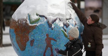 Children clean the snow from a globe in Copenhagen, Denmark, Dec. 17, 2009. (Reuters Photo)