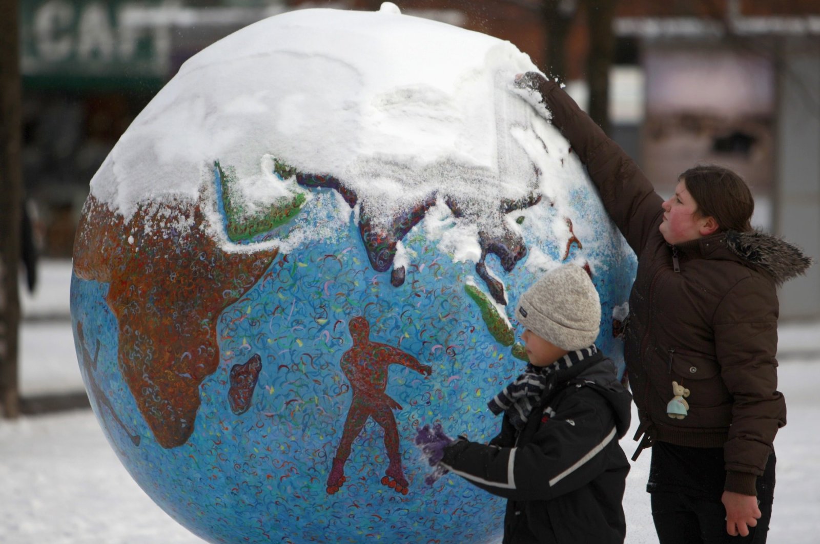 Children clean the snow from a globe in Copenhagen, Denmark, Dec. 17, 2009. (Reuters Photo)