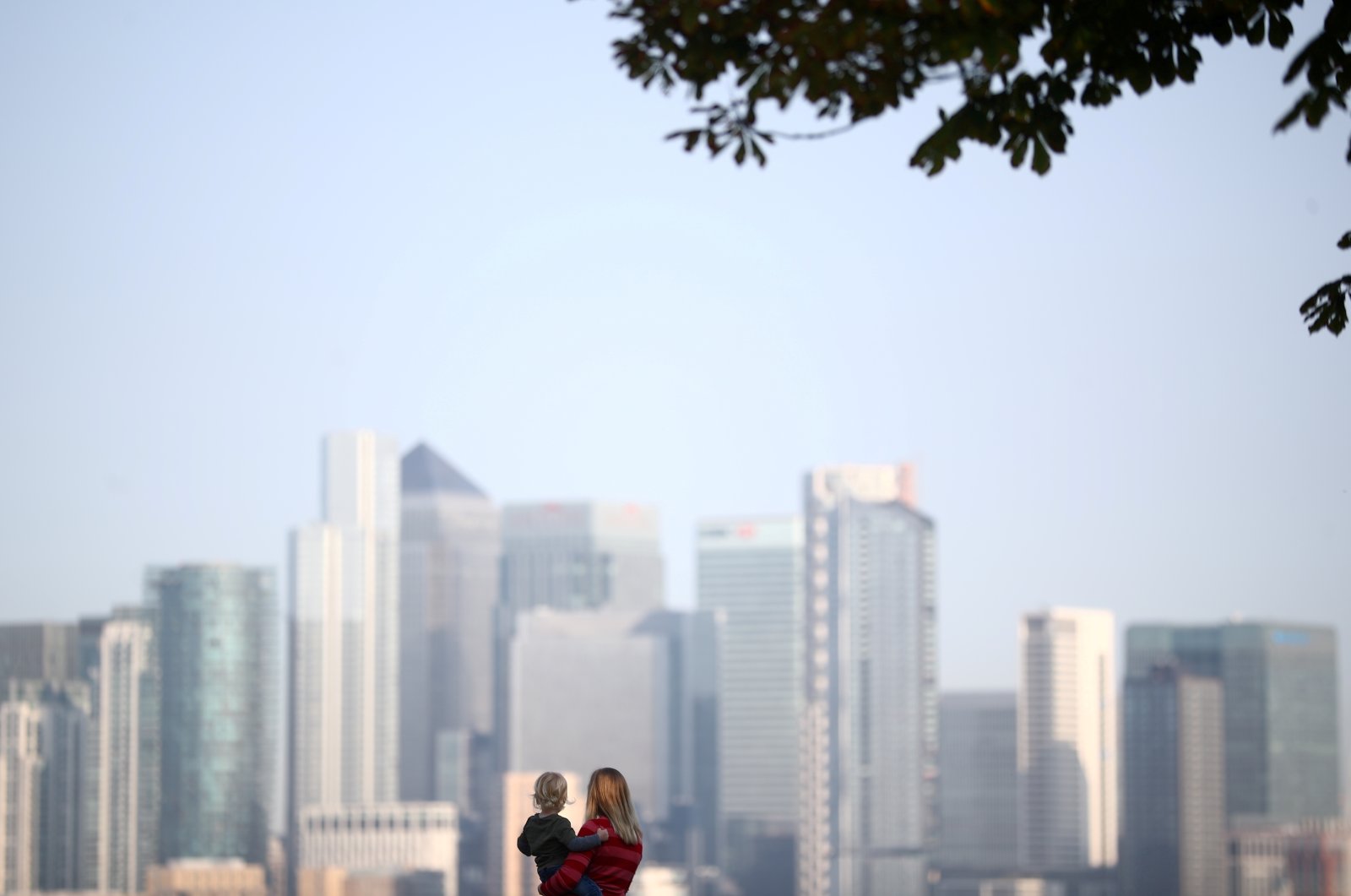 A woman holds a child in front of Canary Wharf skyline, London, U.K., Sept. 14, 2020. (Reuters Photo)