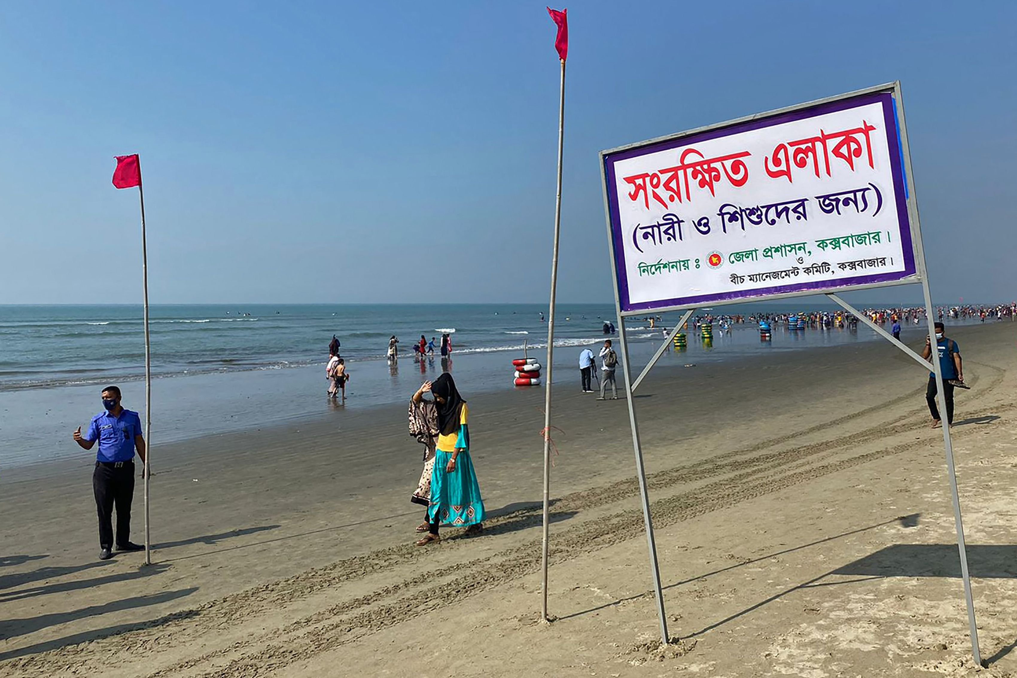 People walk past a signboard reading &quot;Reserved area for women and children as instructed by the district commissioner&quot; along a beach in Cox&#039;s Bazar, Bangladesh, Dec. 30, 2021. (Photo by AFP)