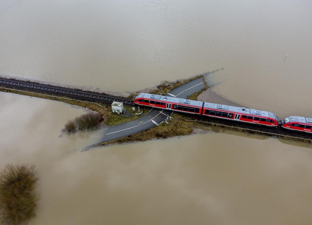 A train passes a railroad crossing surrounded by floodwaters from rain and melting snow in Nidderau near Frankfurt, Germany, Feb. 3, 2021. (AP Photo)