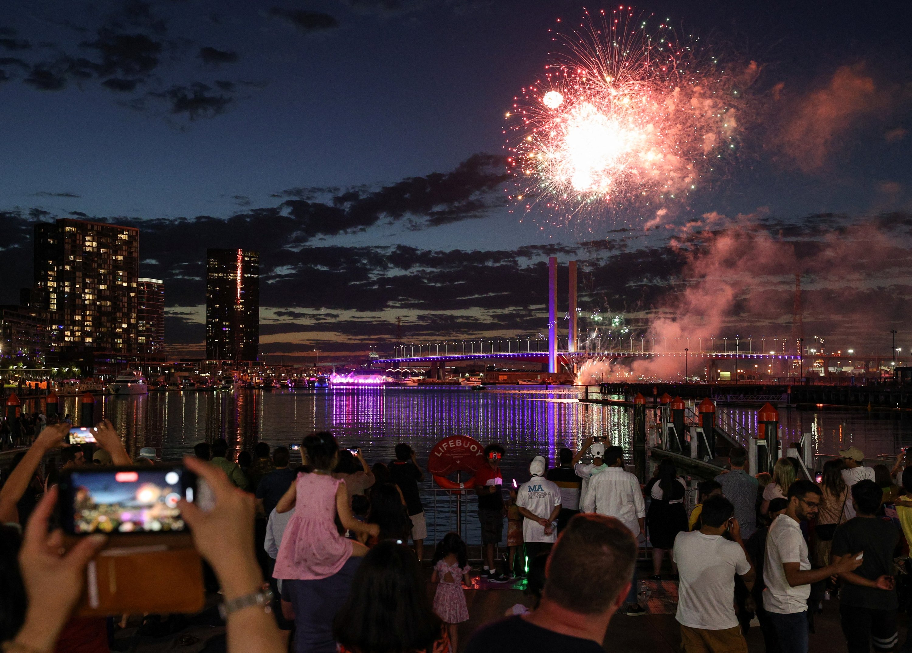 Orang-orang menonton pertunjukan kembang api matahari terbenam untuk anak-anak dan keluarga saat merayakan Malam Tahun Baru di tepi Sungai Yarra, di Melbourne, Australia, 31 Desember 2021. (Foto Reuters)