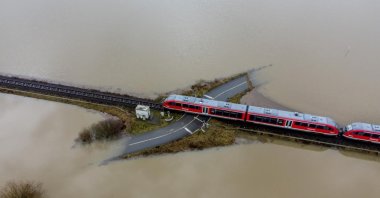 A train passes a railroad crossing surrounded by floodwaters from rain and melting snow in Nidderau near Frankfurt, Germany, Feb. 3, 2021. (AP Photo)