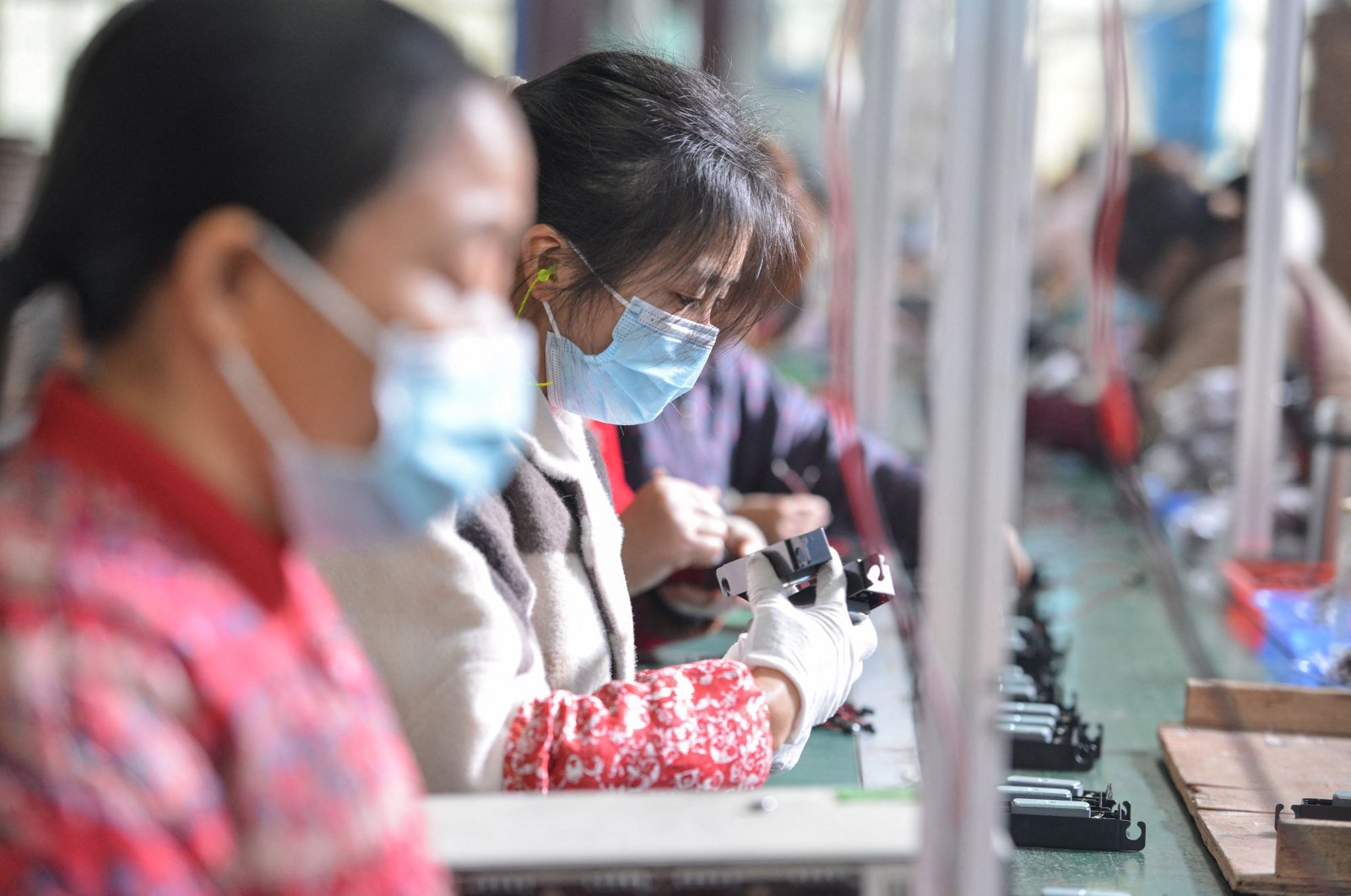 This file photo shows women working on an assembly line producing speakers at a factory in Fuyang, in the eastern Anhui province, China, Nov. 30, 2021. (AFP Photo)