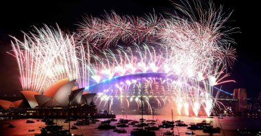 New Year's Eve fireworks light up the sky over Sydney's iconic Harbour Bridge and Opera House (L) during the fireworks show on Sydney, Australia, Jan. 1, 2022. (AFP Photo)