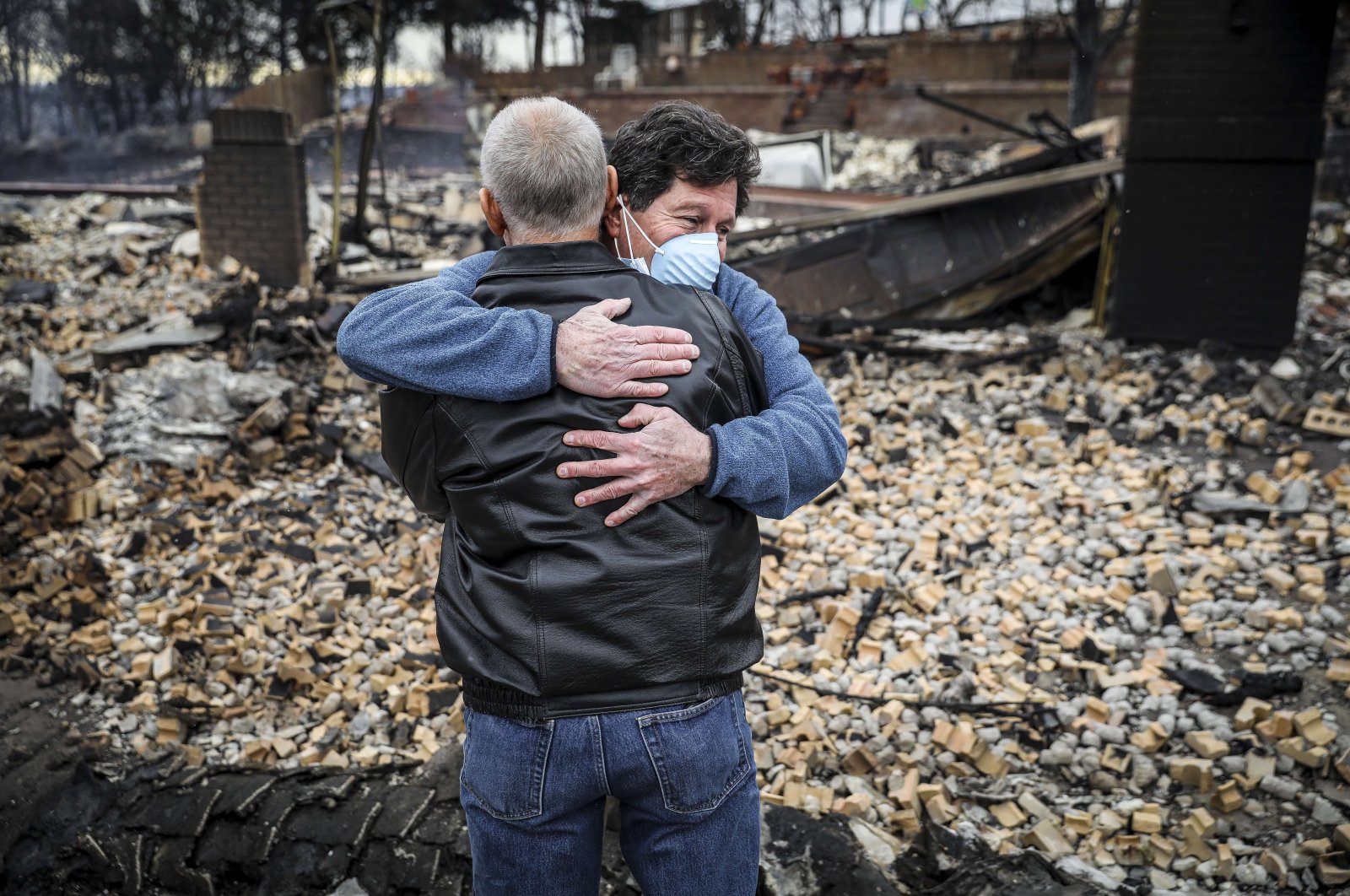 Neighbors Louie Delaware (L) and Roy Nelson hug in the rubble of Delaware&#039;s home in the aftermath of the Marshall Fire in Louisville, Colorado, Dec. 31, 2021. (Getty Images/AFP Photo)