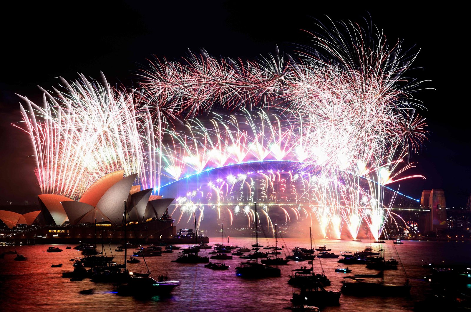 New Year&#039;s Eve fireworks light up the sky over Sydney&#039;s iconic Harbour Bridge and Opera House (L) during the fireworks show on Sydney, Australia, Jan. 1, 2022. (AFP Photo)