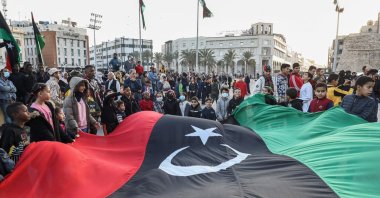 Children wave a giant Libyan national flag as people gather at Martyrs&#039; Square in the center of the capital Tripoli, Libya, Dec. 24, 2021. (AFP Photo)