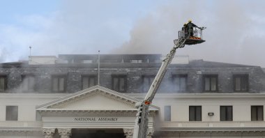 Firefighters are lifted by a crane to survey the damage of the Parliament building where a fire broke out, in Cape Town, South Africa, Jan. 2, 2022. (Reuters Photo)