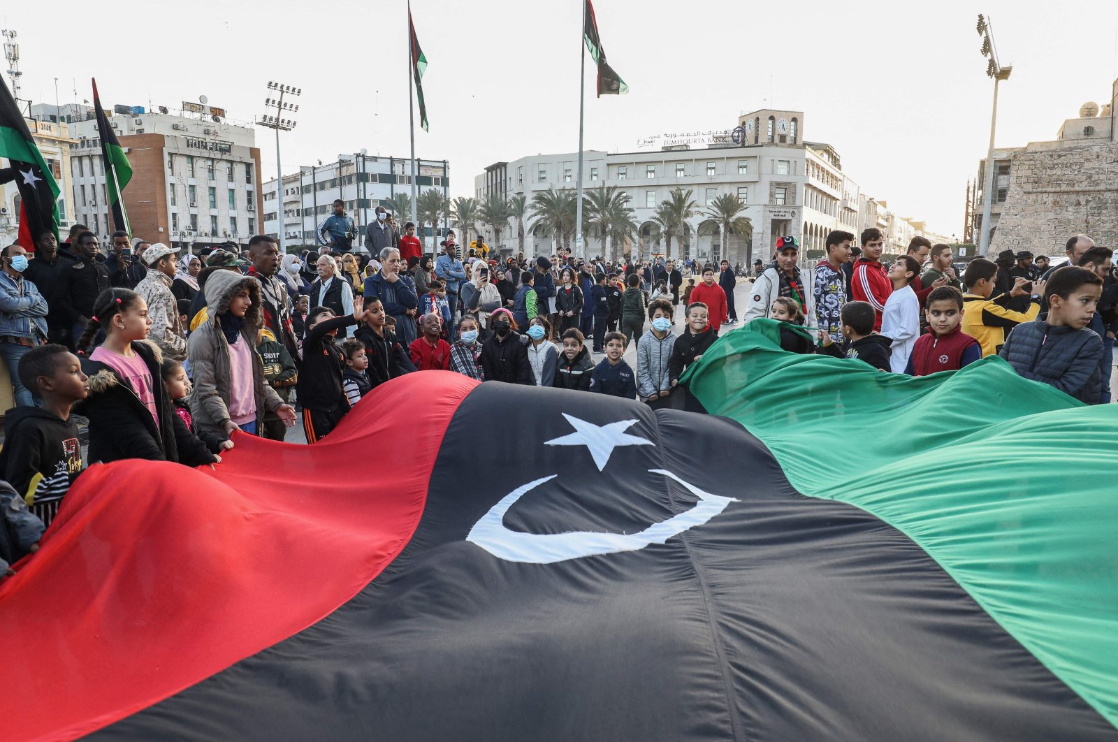 Children wave a giant Libyan national flag as people gather at Martyrs&#039; Square in the center of the capital Tripoli, Libya, Dec. 24, 2021. (AFP Photo)