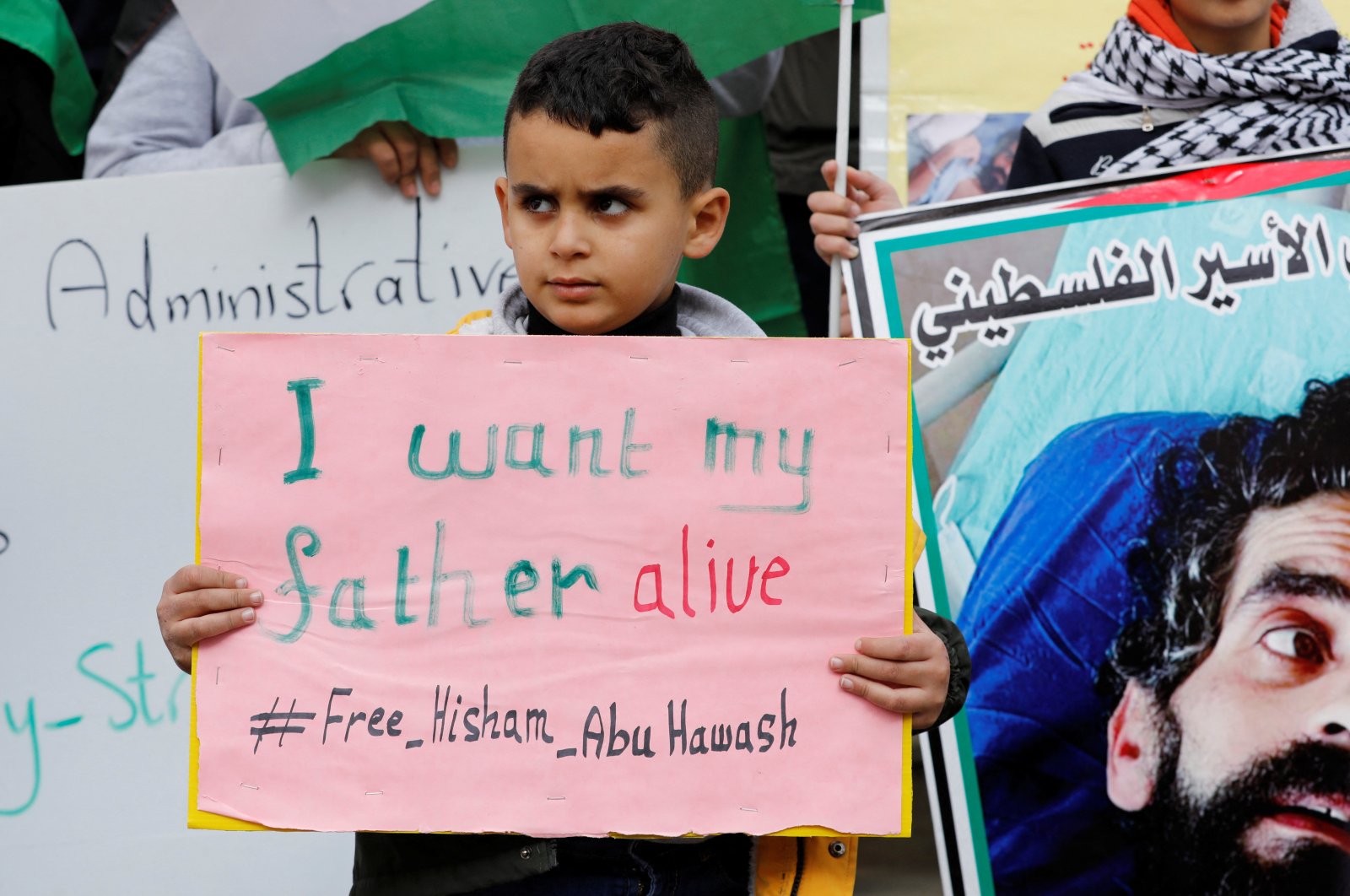 Izz, son of the hunger-striking Palestinian prisoner Hisham Aby Hawash held by Israel, holds a sign during a protest in solidarity with him in Dura, in the Israeli-occupied West Bank, Jan. 2, 2022. (REUTERS)