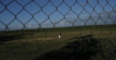 A Haitian child carries a container filled with water across an improvised soccer field in the Batey La Lima community, in La Romana, Dominican Republic, Nov. 17, 2021. (AP Photo)