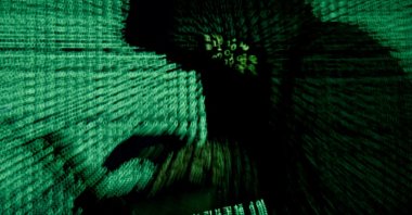 A man holds a laptop as cyber code is projected on him in this illustration picture taken on May 13, 2017. (Reuters Photo)