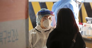 A medical worker wearing protective gear takes a sample from a woman at a temporary screening clinic for the coronavirus in Gwangju, South Korea, Jan. 3, 2022. (AP Photo)
