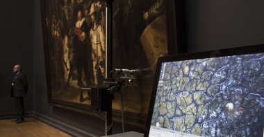 A microscopic image enlarging a 4x6 millimeter part of the painting on Rembrandt's "Night Watch" is seen on a screen next to the painting at the Rijksmuseum in Amsterdam, Netherlands, Oct. 16, 2018. (AP Photo/Peter Dejong)
