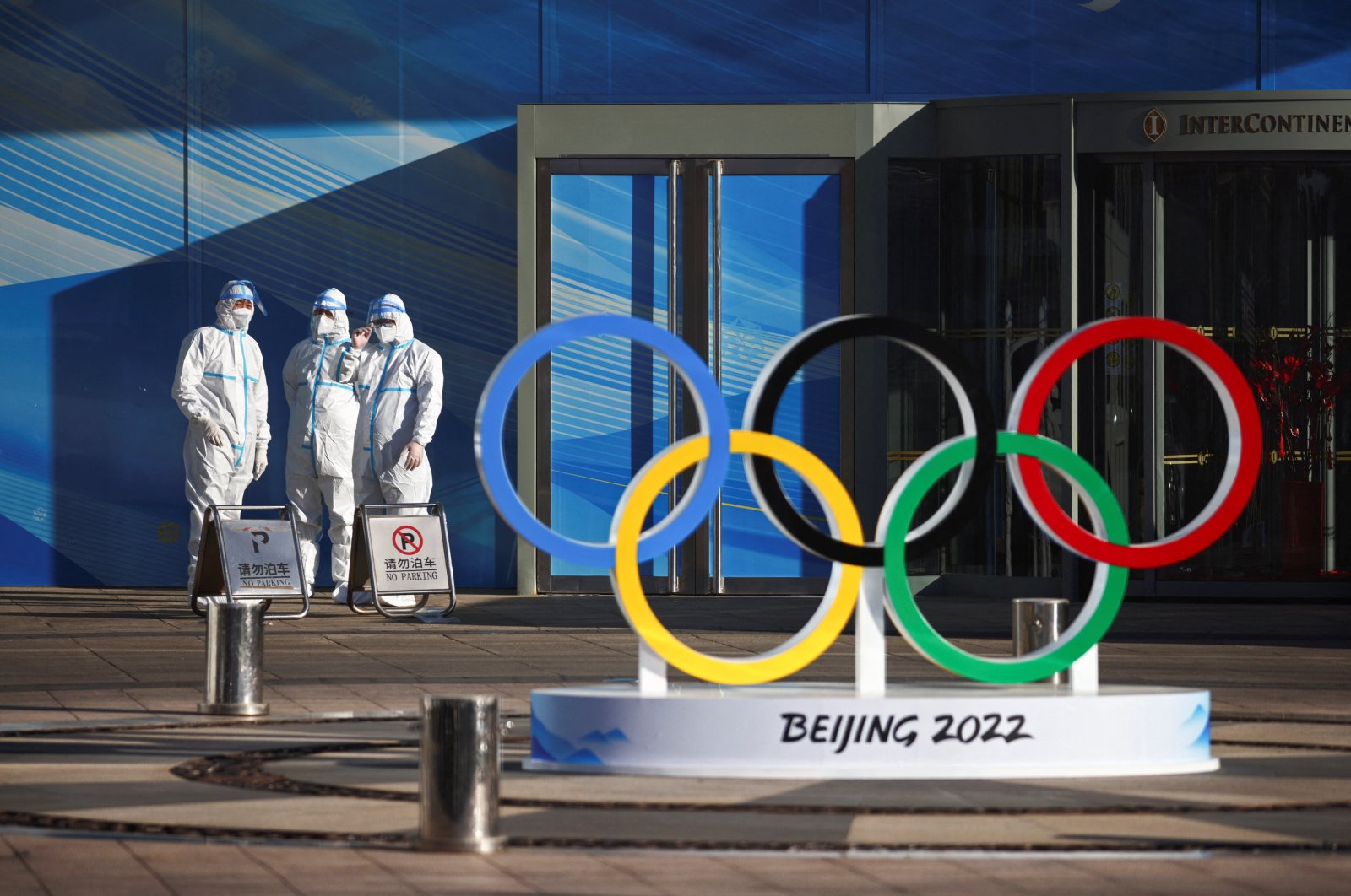 Workers in PPE stand next to the Olympic rings inside the closed-loop area near the Bird&#039;s Nest in Beijing, China, Dec. 30, 2021. (Reuters Photo)