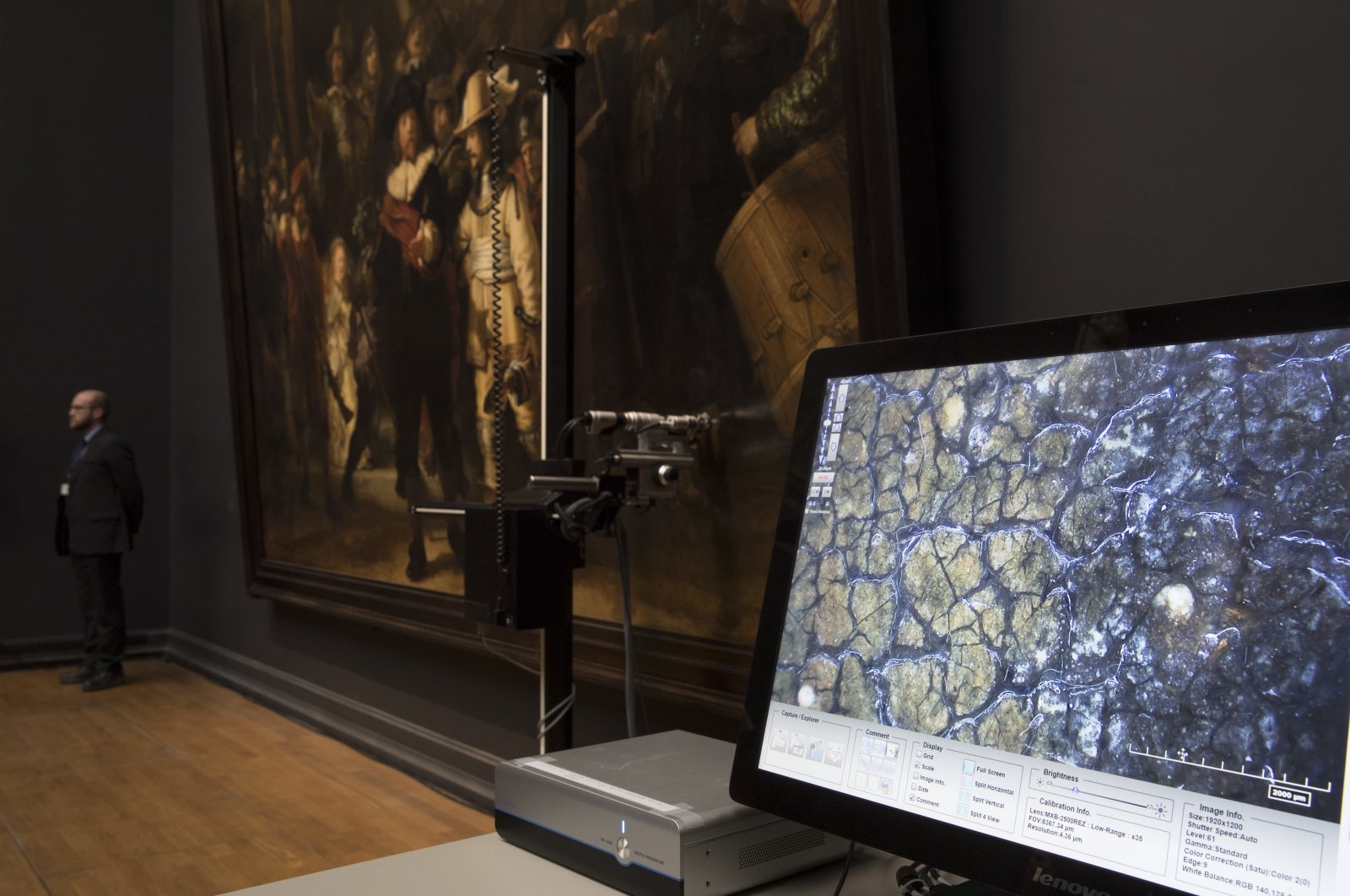 A microscopic image enlarging a 4x6 millimeter part of the painting on Rembrandt&#039;s "Night Watch" is seen on a screen next to the painting at the Rijksmuseum in Amsterdam, Netherlands, Oct. 16, 2018. (AP Photo/Peter Dejong)