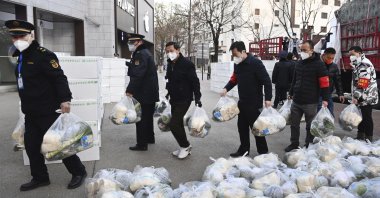 In this photo released by Xinhua News Agency, subdistrict office staff carry daily necessities to be delivered to households under closed-off management in Xi'an, in northwestern China's Shaanxi Province, Dec. 29, 2021. (AP Photo)
