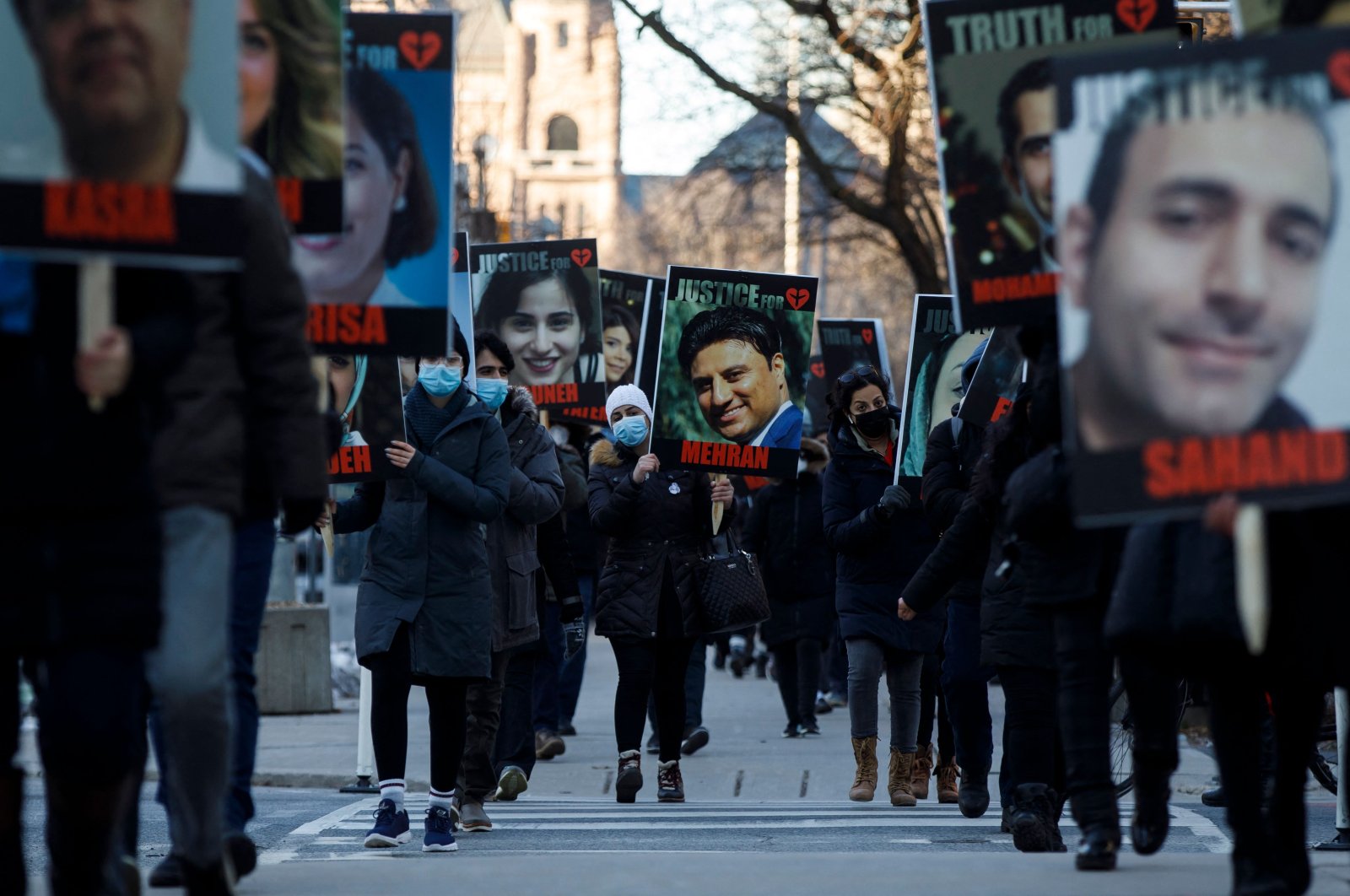 People hold signs with images of the victims of the downed Ukraine International Airlines flight PS752, which was shot down near Tehran by Iran&#039;s Revolutionary Guard, as family and friends gather to take part in a march to mark the first anniversary, in Toronto, Ontario, Canada, Jan. 8, 2021. (AFP Photo)