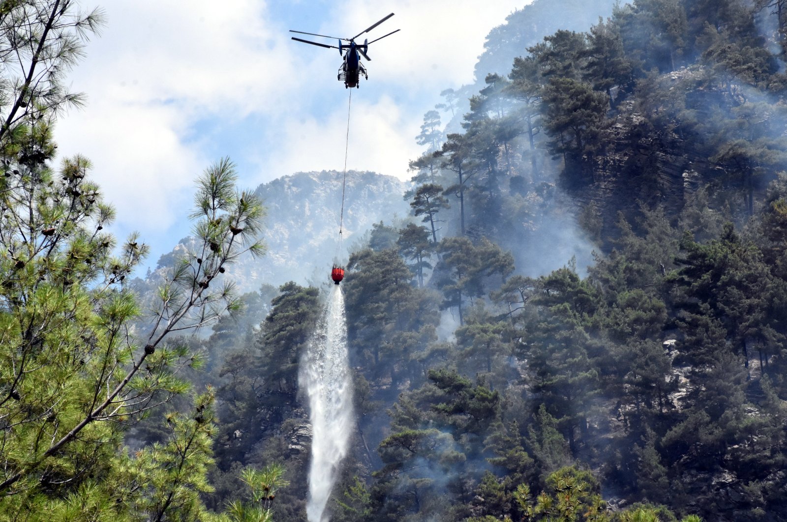 A helicopter drops water on a burning forest, in Muğla, southwestern Turkey, Sept. 8, 2018. (AA PHOTO) 