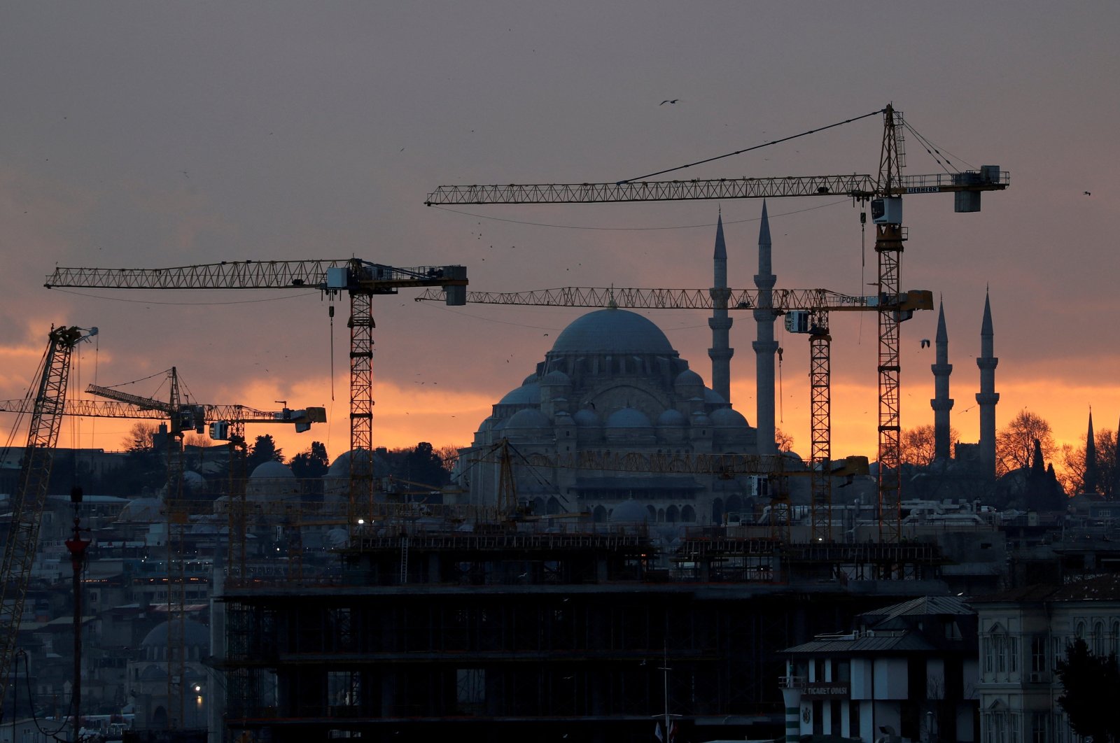 The sun sets behind the cranes of the Galata Port construction site and a mosque in Istanbul, Turkey, Jan. 23, 2020. (Reuters File Photo)