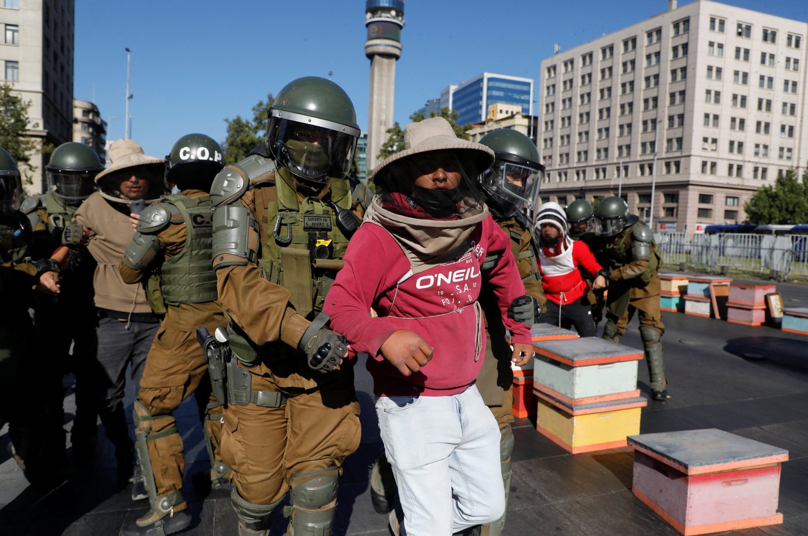 Beekeepers who demanded government measures to face the persistent drought that affects the country are detained by riot police after they blocked the street with honeycombs full of bees in front of the Chilean presidential palace, Santiago, Chile, Jan. 3, 2022. (Reuters Photo)