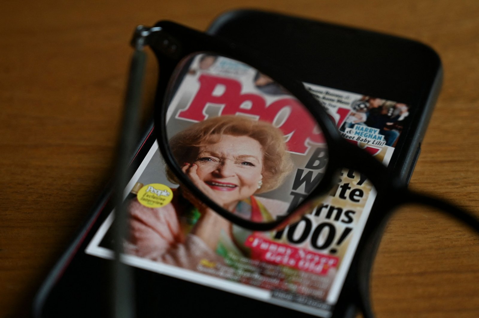 In this photo illustration produced Jan. 1, 2022, in Washington, D.C., a pair of glasses magnify the face of U.S. actress Betty White appearing on the cover of People Magazine. (AFP)