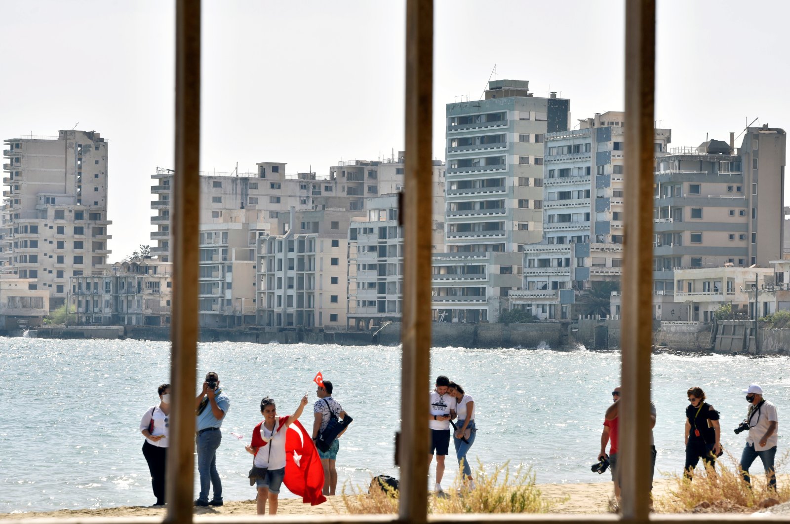 People walk on a beach inside an area fenced off by the Turkish military since 1974 in the abandoned coastal area of Varosha, TRNC, Oct. 8, 2020. (REUTERS Photo)