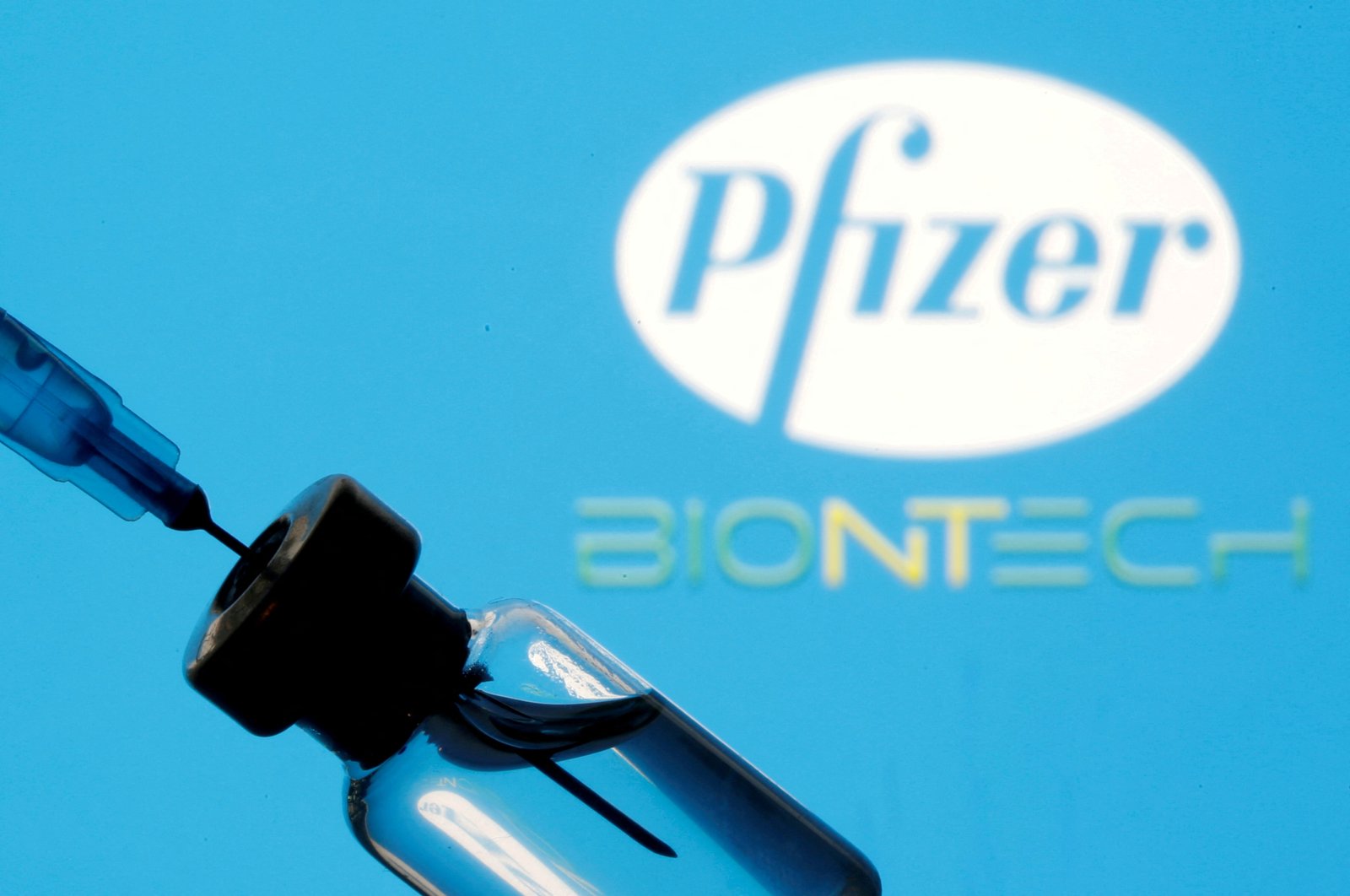 A vial and syringe are seen in front of a Pfizer and BioNTech logo in an illustration, Jan. 11, 2021. (Reuters Photo)