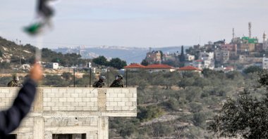 Israeli security forces take position on the roof of a building under construction during clashes with Palestinian protesters in the village of Kfar Qaddum near the settlement of Kedumim in the West Bank, occupied Palestine, Dec. 31, 2021. (AFP Photo)