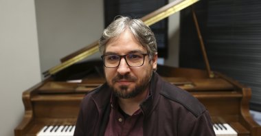 Composer Erberk Eryılmaz poses in front of a piano, Ankara, Turkey, Jan. 5, 2022. (AA)