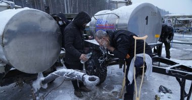 A migrant washes his head with cold water at the "Bruzgi" checkpoint logistics center at the Belarus-Poland border near Grodno, Belarus, Dec. 23, 2021. (AP Photo)