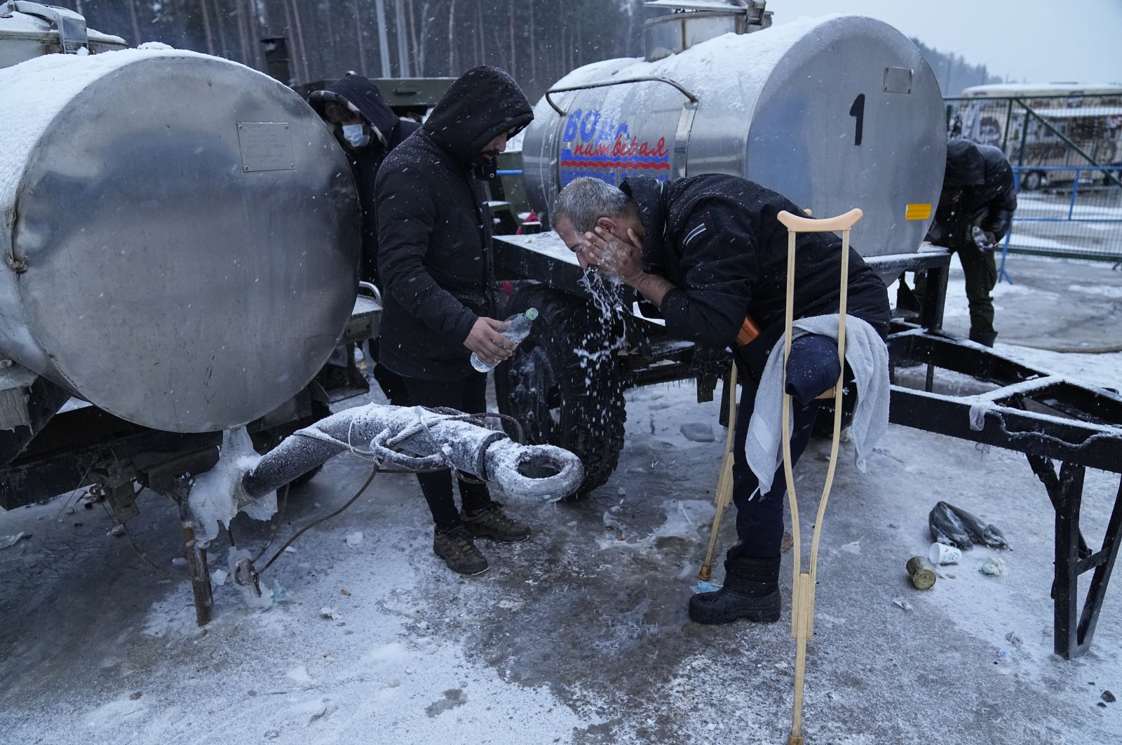 A migrant washes his head with cold water at the &quot;Bruzgi&quot; checkpoint logistics center at the Belarus-Poland border near Grodno, Belarus, Dec. 23, 2021. (AP Photo)