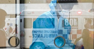 A health worker prepares to perform COVID-19 screening from inside a glass booth at a round the clock testing facility in Chennai, India, on Jan. 06, 2022. (AFP Photo)