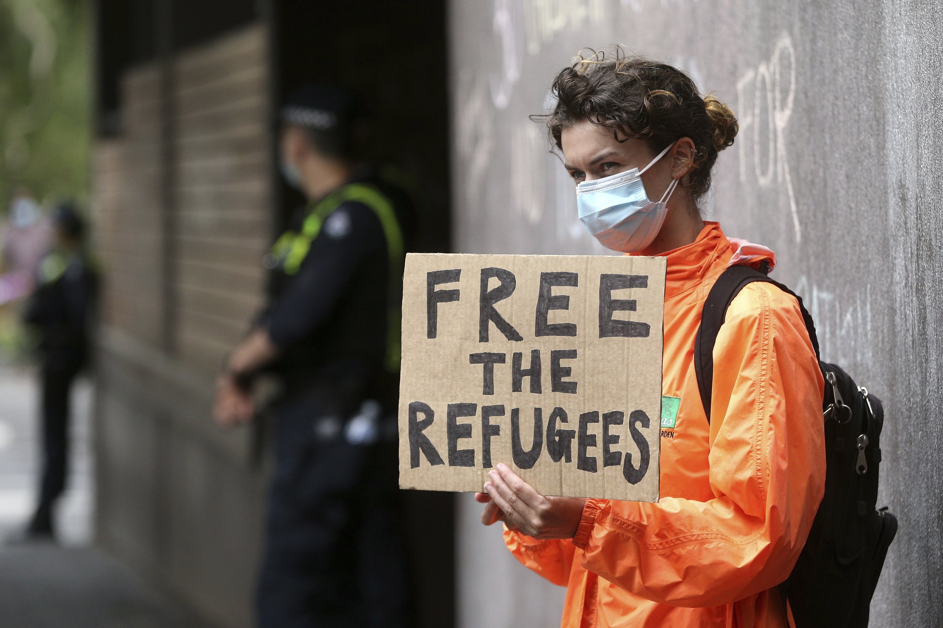 A protester holds a banner outside the Park Hotel calling for the release of refugees being detained inside the hotel in Melbourne, Australia, Jan. 8, 2022. (AP Photo)