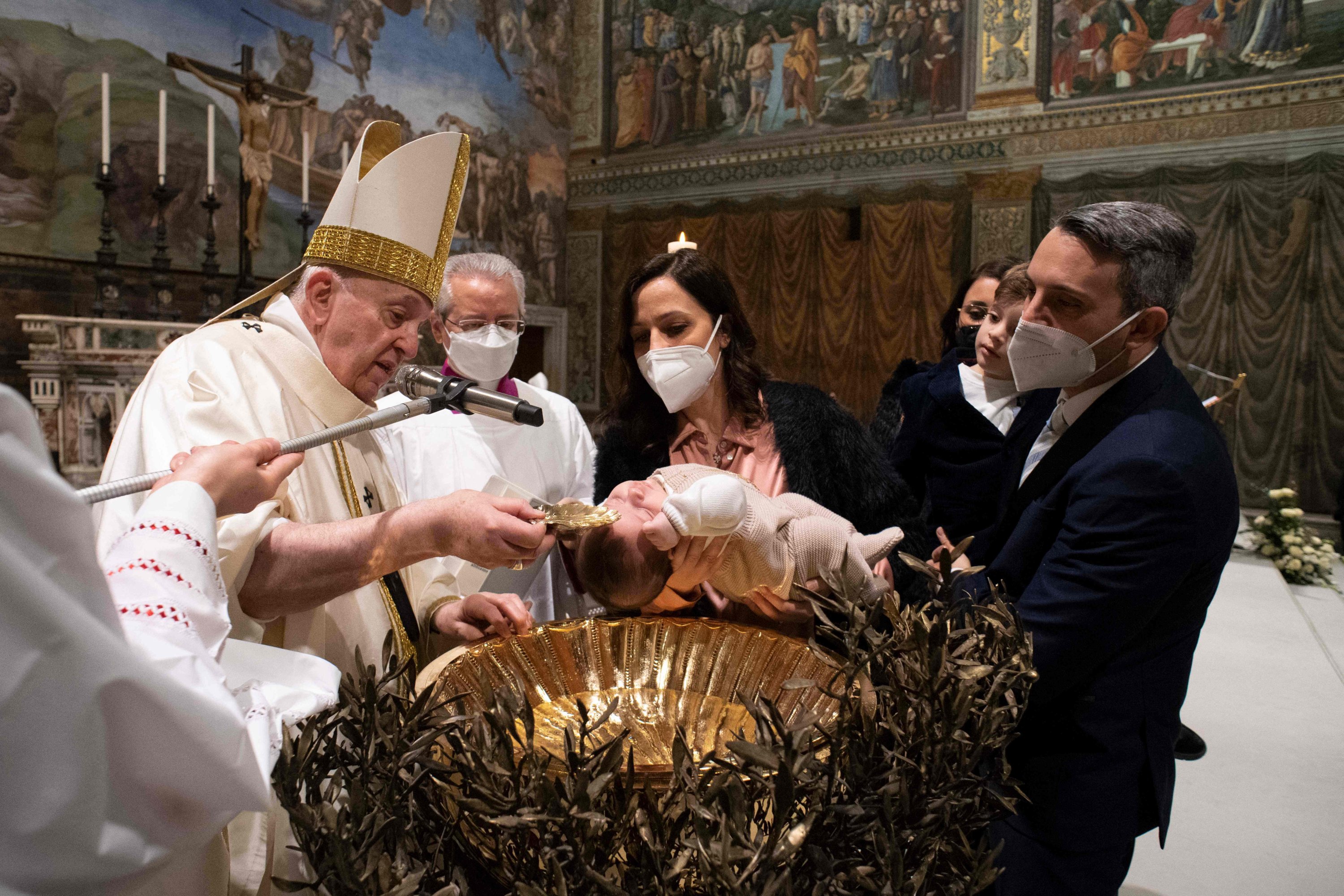 A handout picture taken and released on January 9, 2022 by the Divisione Produzione Fotografica shows Pope Francis baptising a child during the Holy Mass in the Sistine Chapel in Vatican. (Photo by Simone Risoluti/Divisione Produzione Fotografica via AFP)