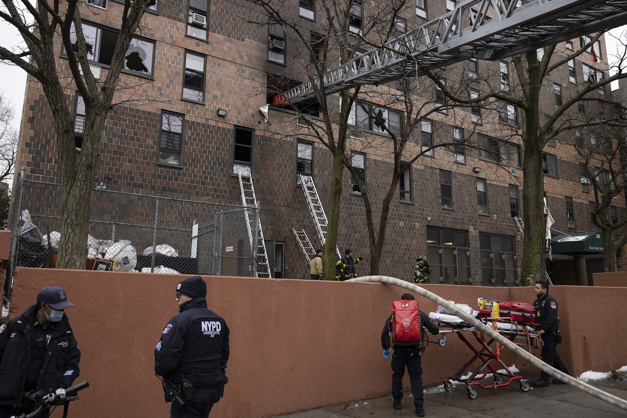 Petugas pemadam kebakaran dan petugas NYPD bekerja di luar gedung apartemen setelah kebakaran di wilayah Bronx, New York City, AS, 9 Januari 2022. (AP Photo)