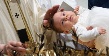 A handout picture taken and released on Jan. 9, 2022, by the Divisione Produzione Fotografica shows Pope Francis baptising a child during the Holy Mass in the Sistine Chapel in Vatican. (Photo by Simone Risoluti RISOLUTI/Divisione Produzione Fotografica via AFP)