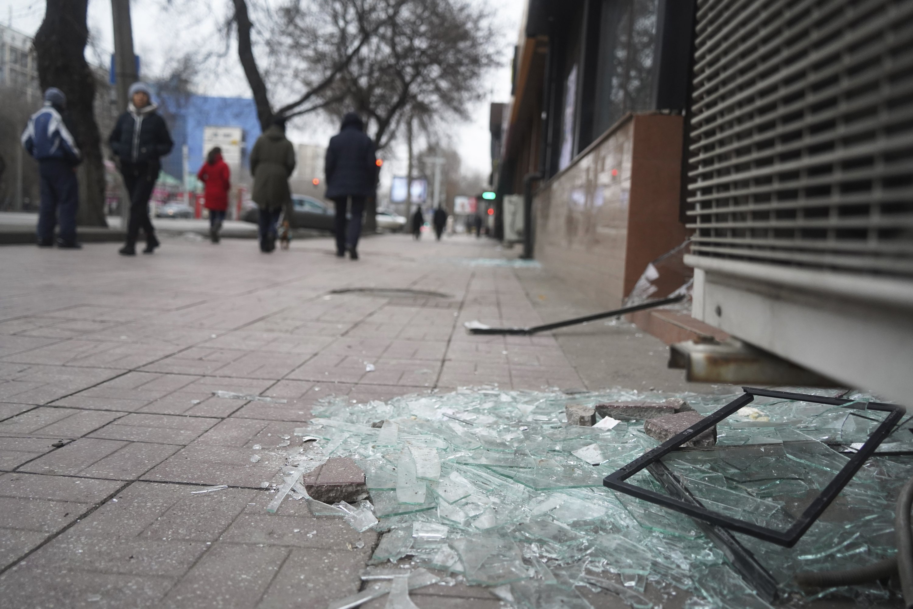 People walk past a shop with windows broken during clashes in Almaty, Kazakhstan, Jan. 10, 2022. (AP Photo)