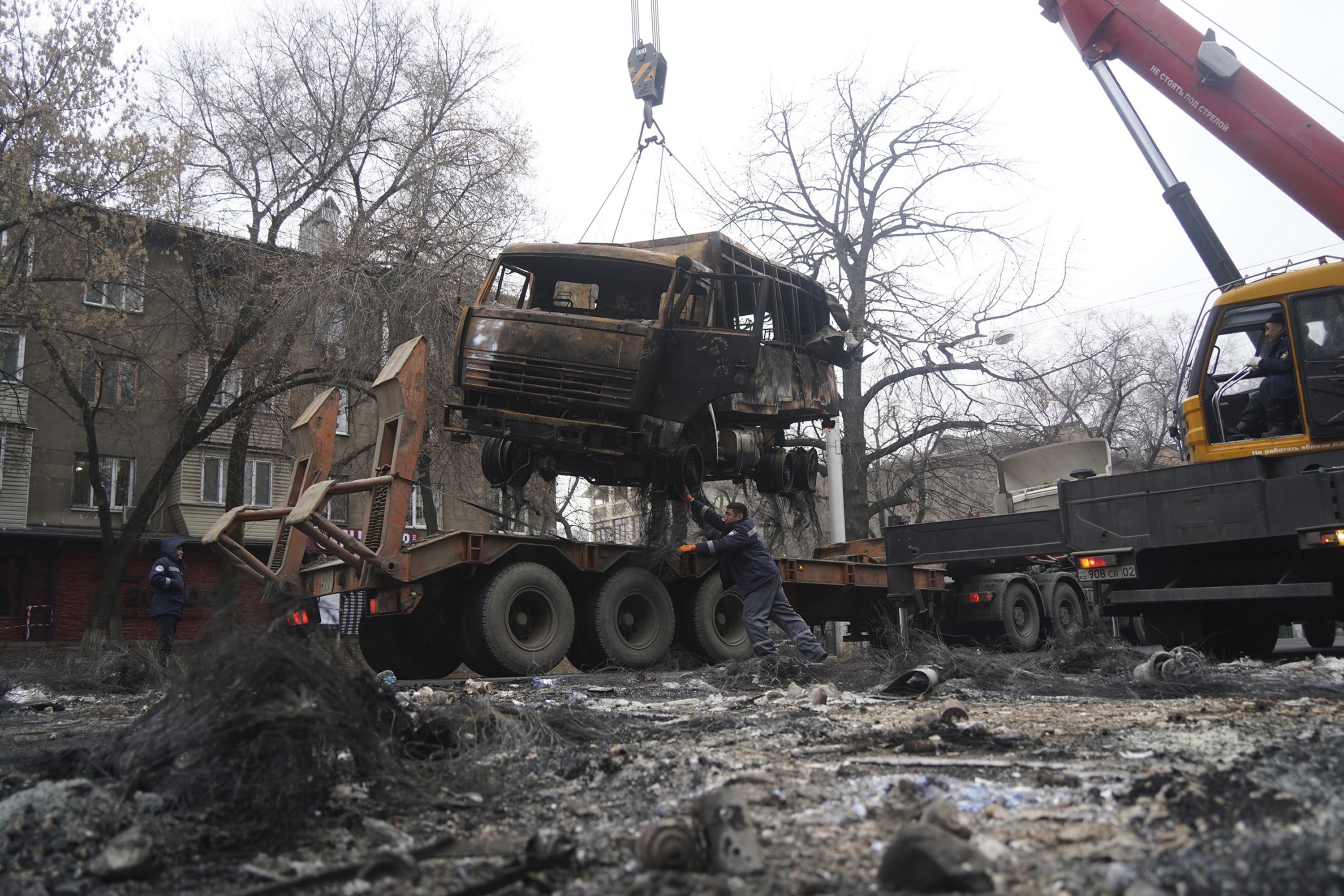 A crane loads a military truck, which was burned during clashes onto the platform in Almaty, Kazakhstan, Jan. 9, 2022. (AP Photo)