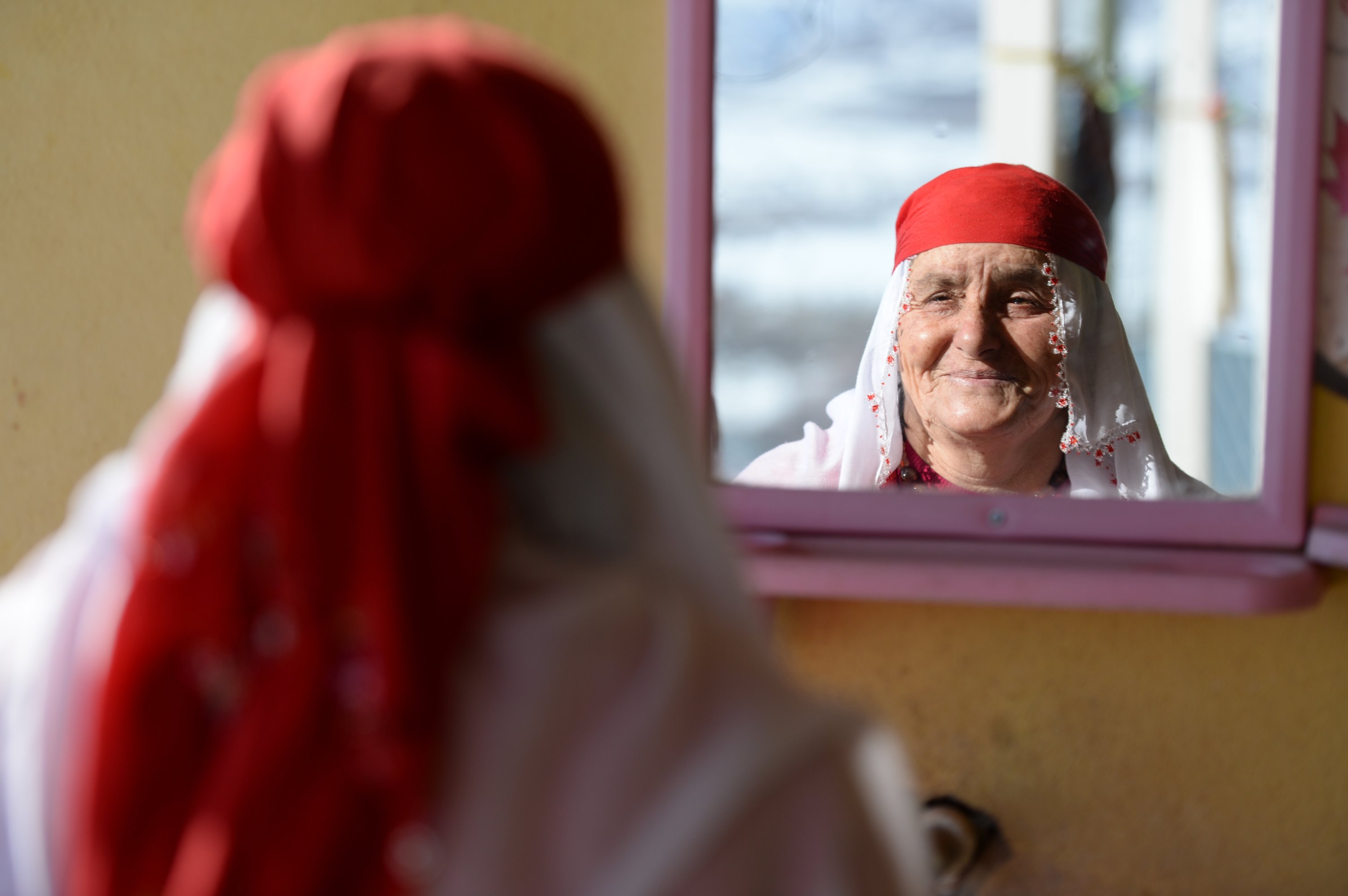Wanita berbaju merah, Nafiye Caz, melihat ke cermin, Bingöl, Turki, 10 Januari 2022. (AA Photo)