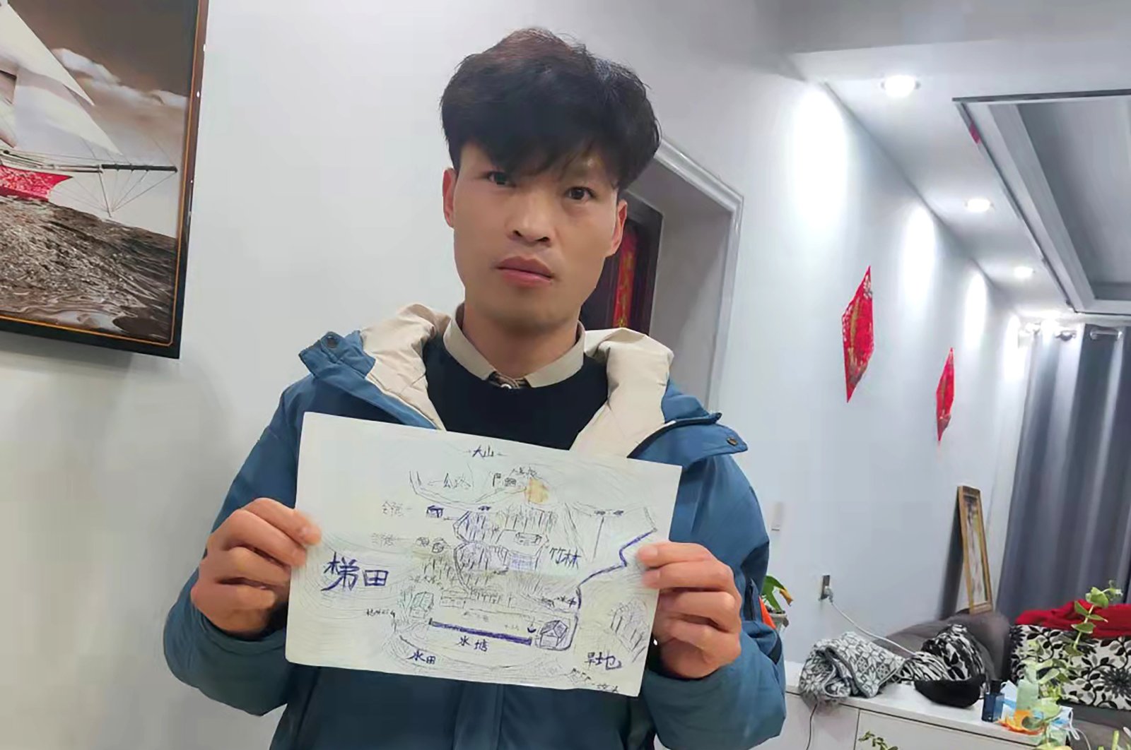 Li Jingwei holds a map he drew from memory of his childhood village as he poses for a photo in Lankao in central China&#039;s Henan Province, Wednesday, Jan. 5, 2022. (Li Jingwei via AP)