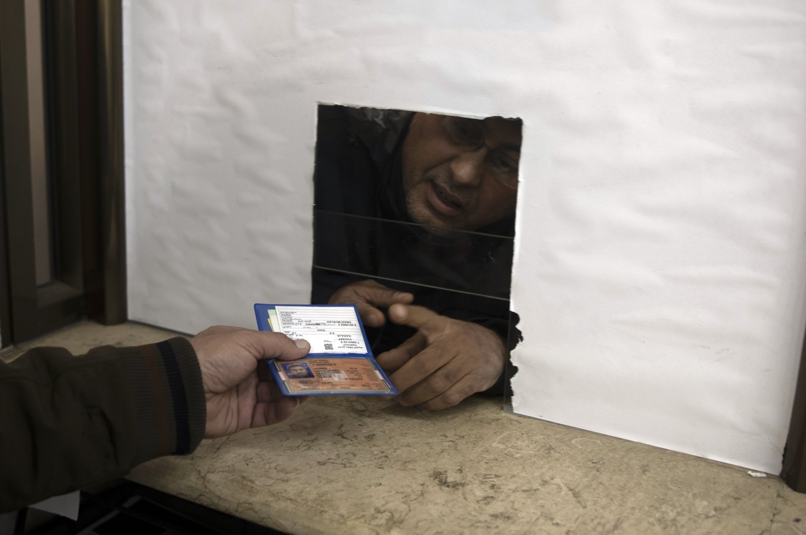 A Palestinian man hands over his temporary ID to a civil affairs employee to get his officially approved register letter, in Gaza City, Palestine, Jan. 3, 2022. (AP Photo)