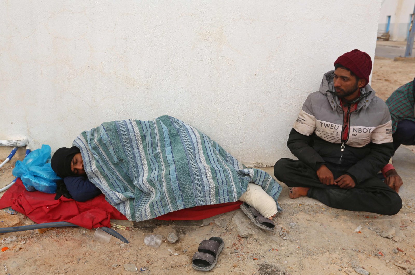 Migrants rescued by Tunisia&#039;s national guard during an attempted crossing of the Mediterranean by boat, rest on the beach at the port of el-Ketef in Ben Guerdane in southern Tunisia near the border with Libya, on Jan. 6, 2022. (AFP)