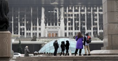 People look at the burnt city hall building in the central square blocked by Kazakh troops and police in Almaty, Kazakhstan, Jan. 11, 2022. (AP Photo)