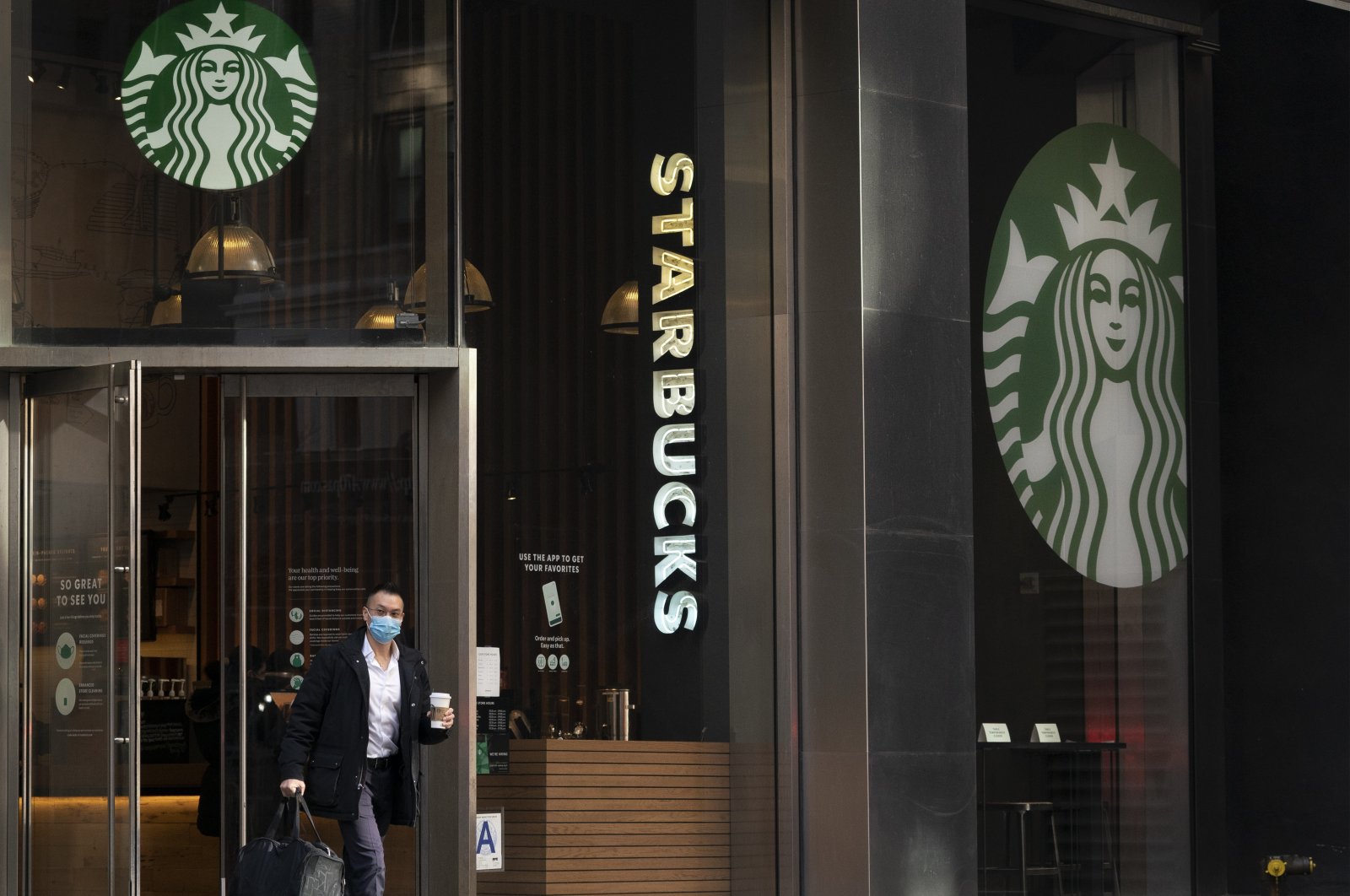 A man carries a beverage as he walks out of a Starbucks coffee shop in New York, U.S., Jan. 19, 2021. (AP Photo)