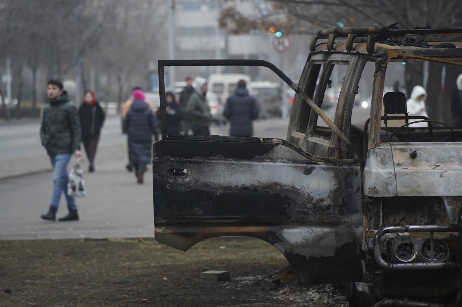 People walk past a bus burned during clashes in Almaty, Kazakhstan, Jan. 11, 2022. (Vladimir Tretyakov/NUR.KZ via AP)