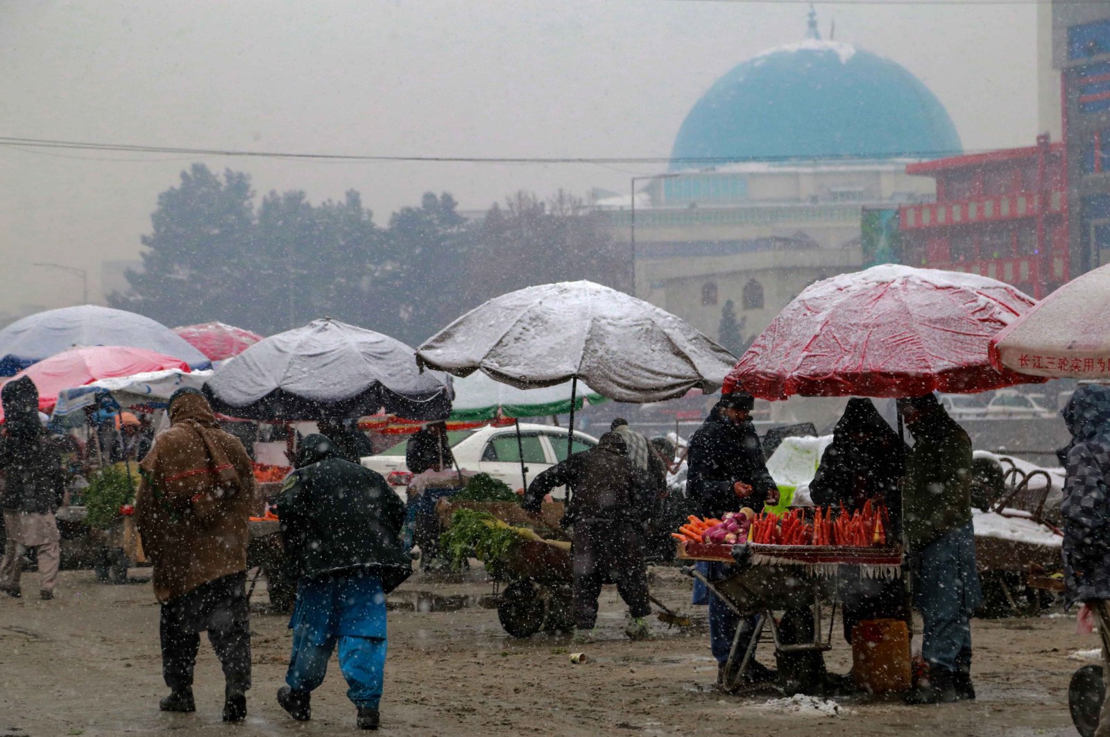Pedestrians pass street vendors as snow falls in Kabul, Afghanistan, Jan. 3, 2022. (EPA Photo)