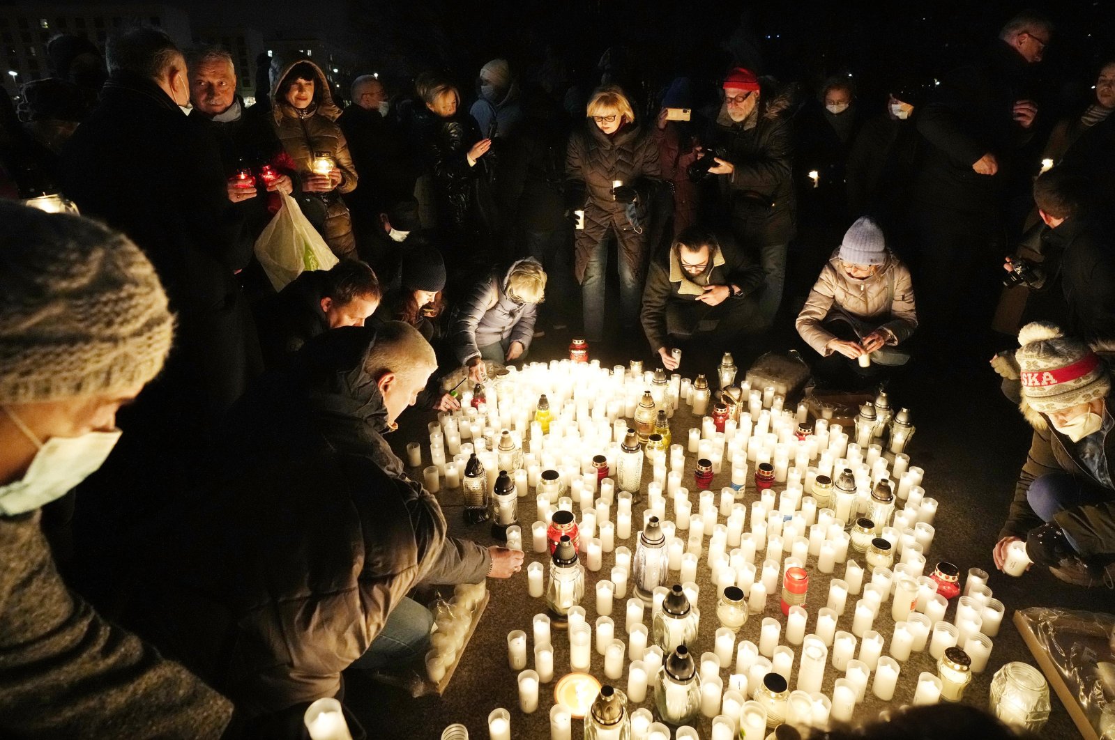 People light candles to commemorate those who who have died from COVID-19 as Poland hit the sad milestone of 100,000 deaths related to the coronavirus, in Warsaw, Poland, Jan. 11, 2022. (AP Photo)