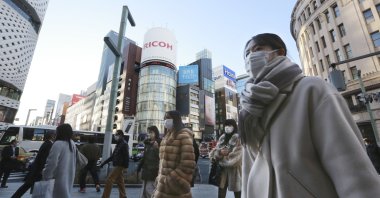 People wearing face masks to contain the spread of the coronavirus walk on the street in Tokyo, Japan, Jan. 12, 2022. (AP Photo)